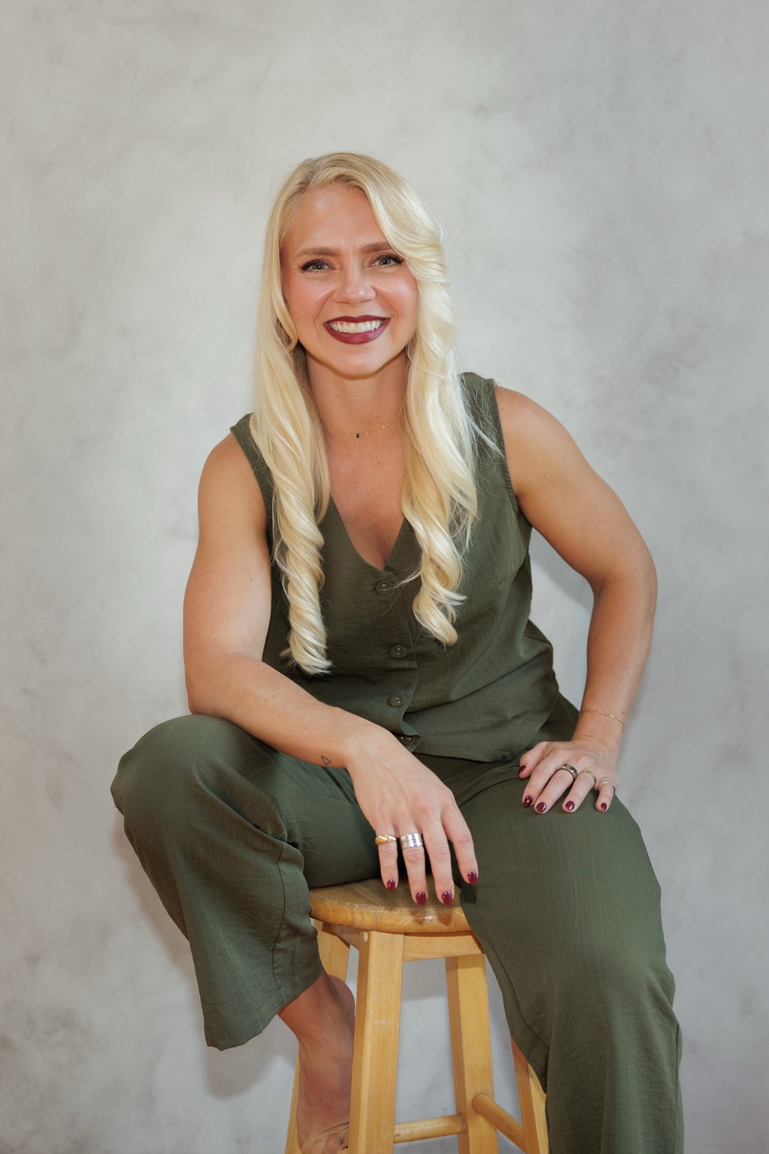 Shaina, founder of The Veracity Co., seated on a stool and laughing